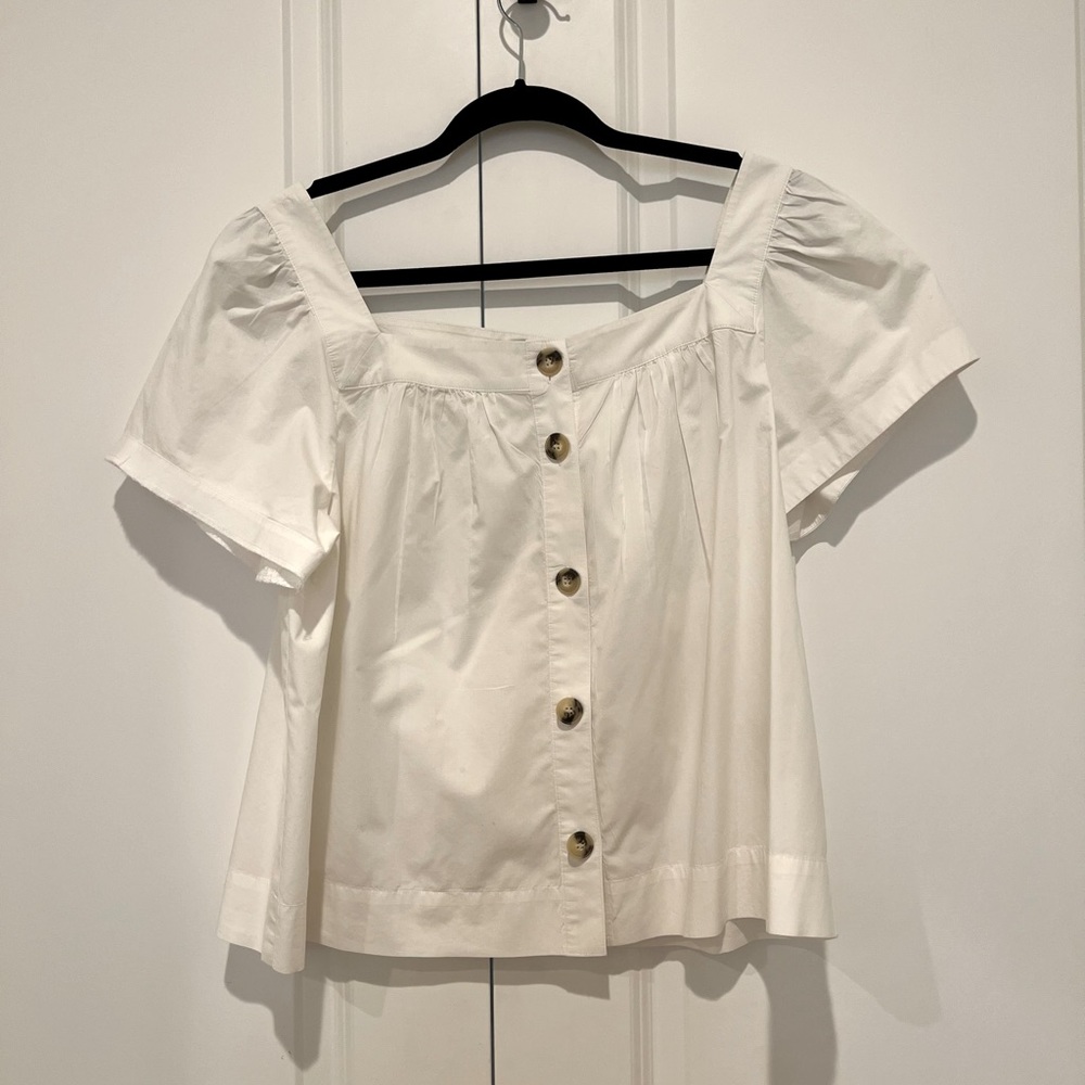 White top with brown buttons and caps sleeve.